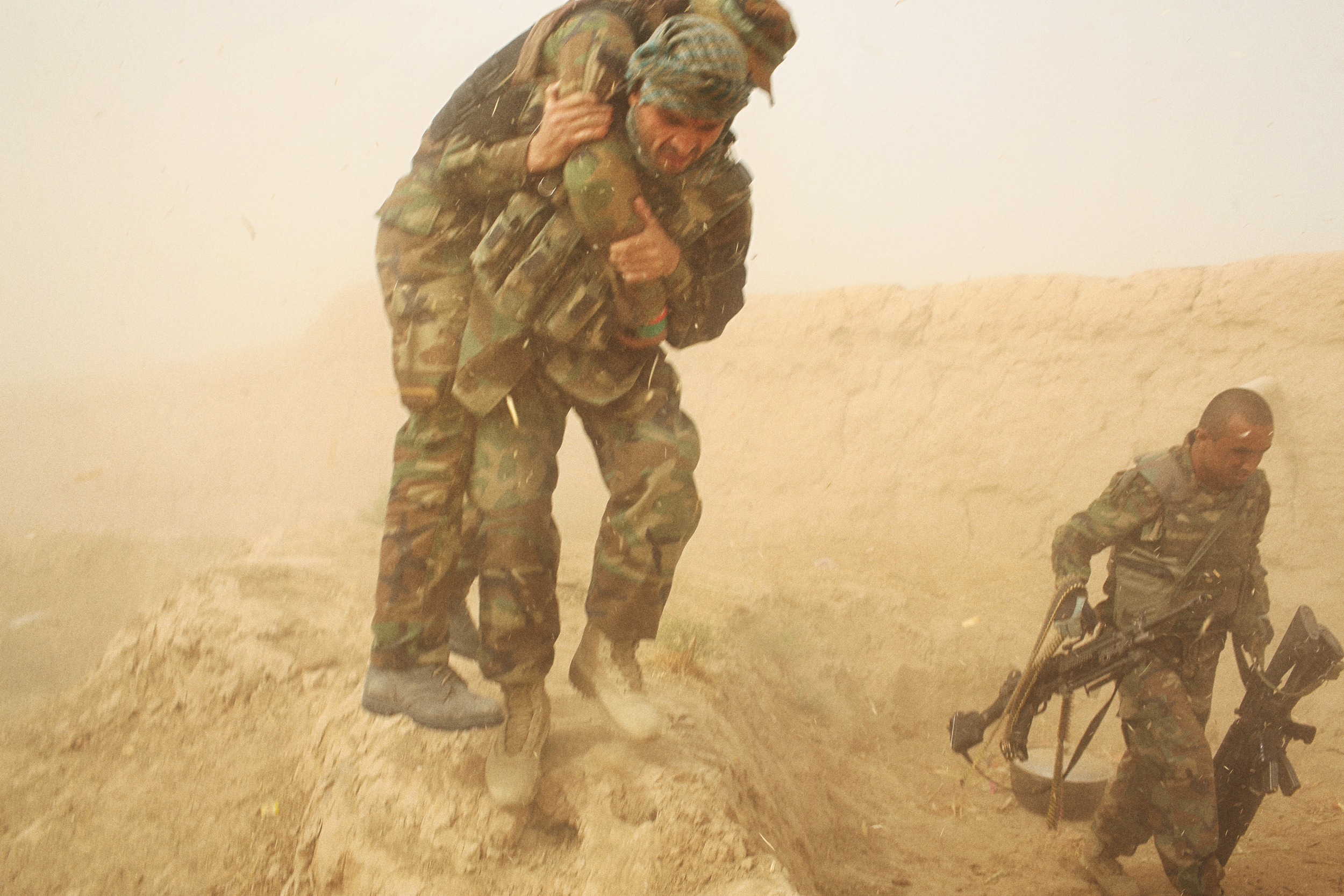  An Afghan National Army soldier carries another soldier after he was wounded by the back-blast of an ANA rocket propelled grenade during the battle to retake the City of Kunduz after the Taliban overran it a week prior. It was the first city to fall to the group since 2001. Kunduz Province, October, 2015. 